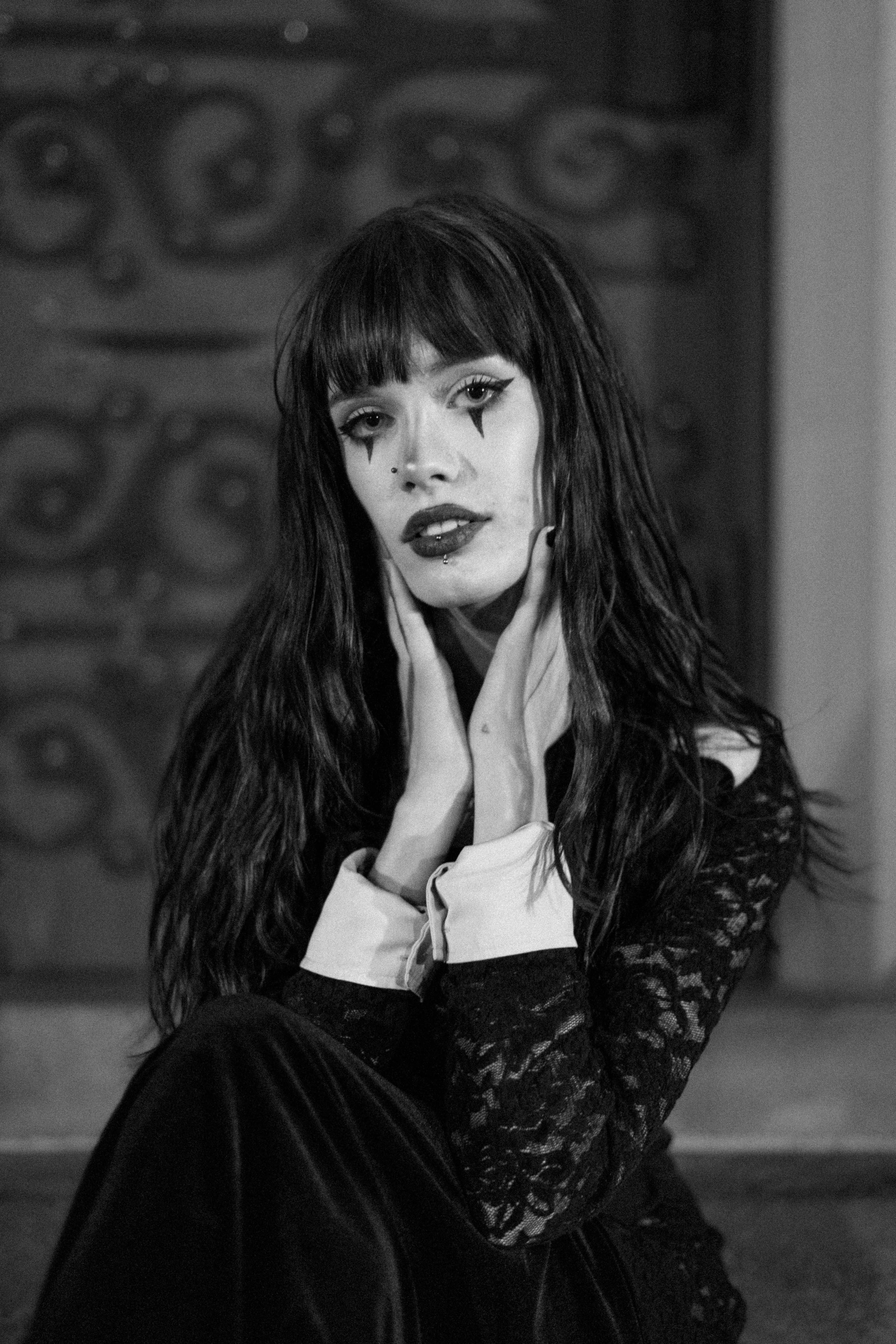 Black and white portrait of a person with clown-inspired makeup and dark hair.